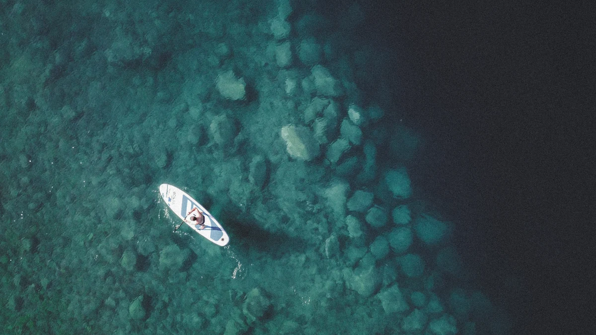 An overhead view of a paddleboard on clear turquoise water