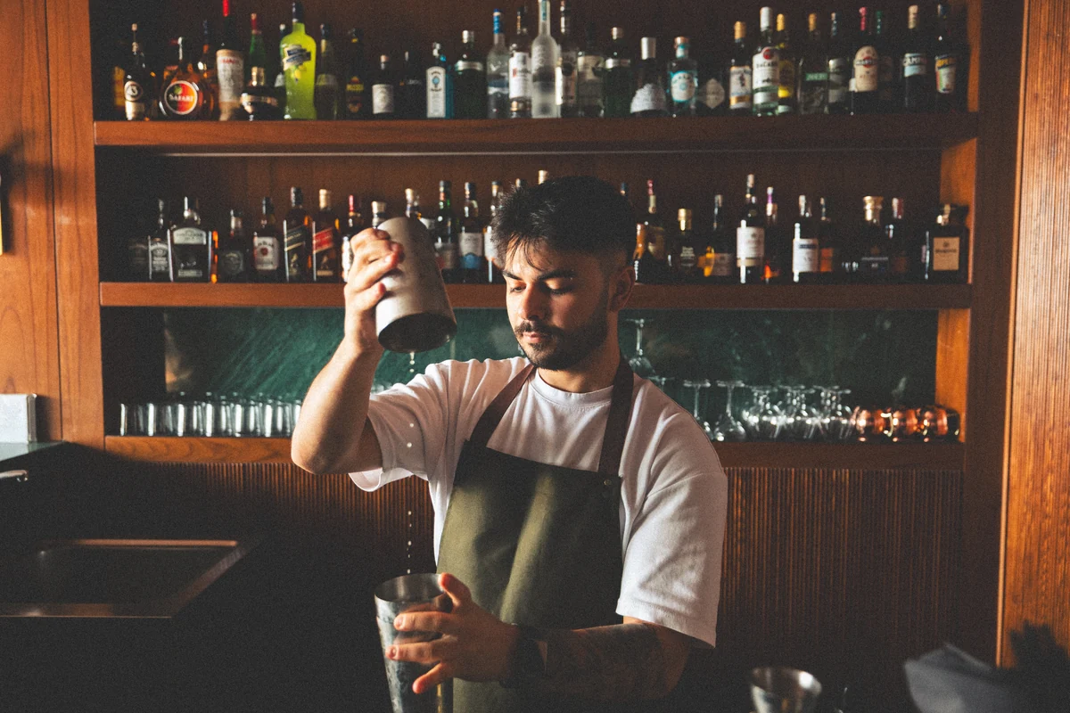 A bartender shaking a cocktail behind the bar