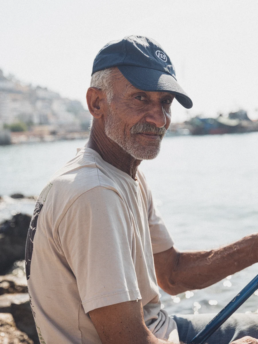 A portrait of a fisherman wearing a navy cap by the sea