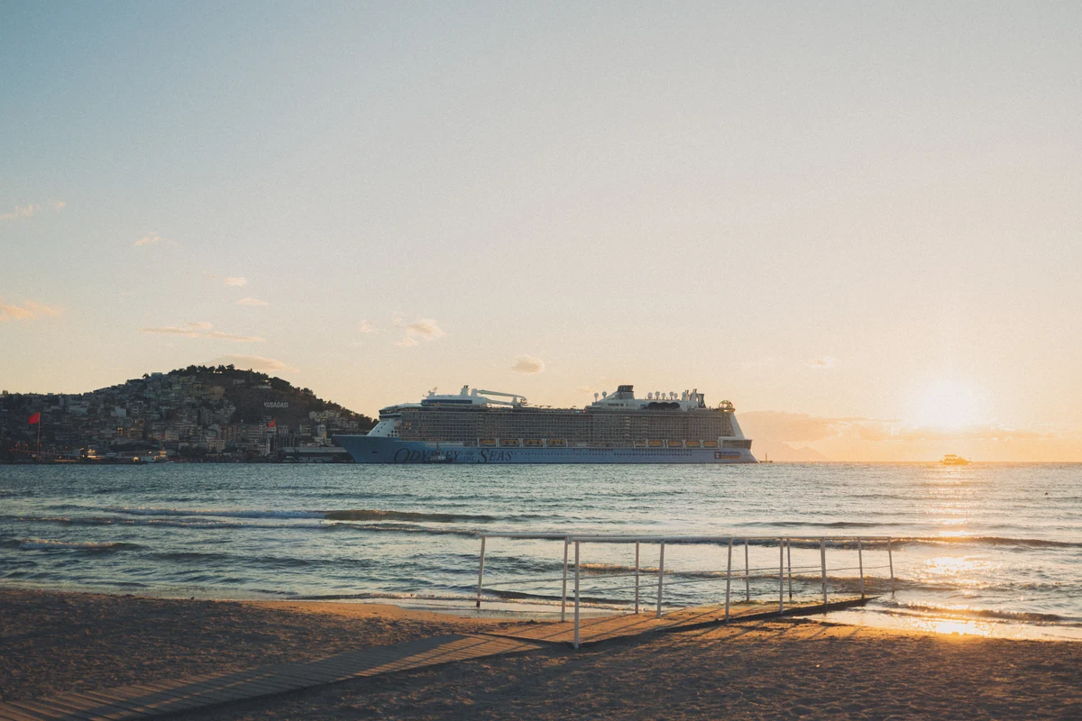 A cruise ship offshore at sunset, seen from the beach