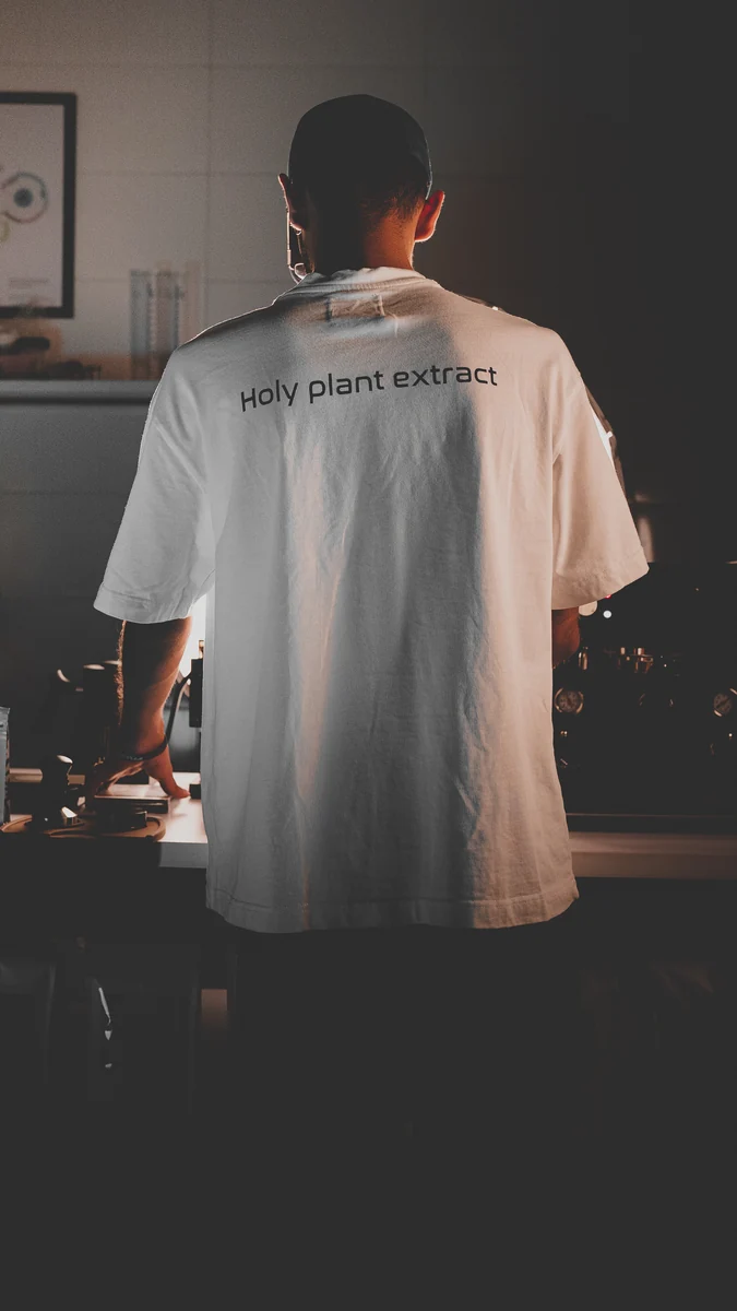 A barista in a white T-shirt seen from behind at a coffee counter